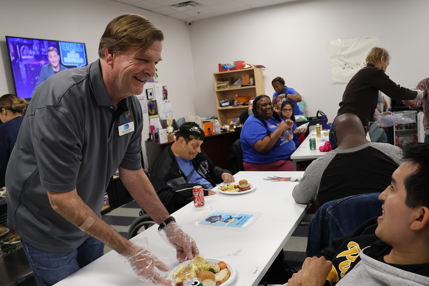 Ability Connection CEO and President Jim Hanophy (left) serves Ability Connection member George during the organization’s annual Thanksgiving feast on Friday, November 22, 2024.