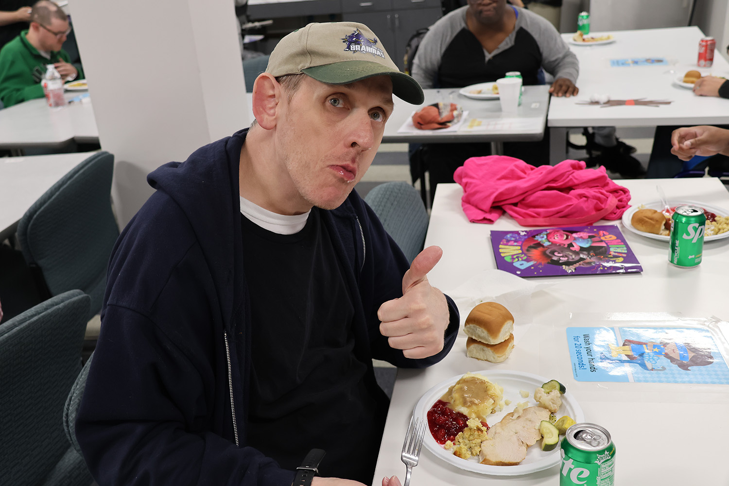 Ability Connection member Shawn gives a thumbs up to the delicious meal provided by Central Market during the Ability Connection annual Thanksgiving feast on Friday, November 22, 2024.